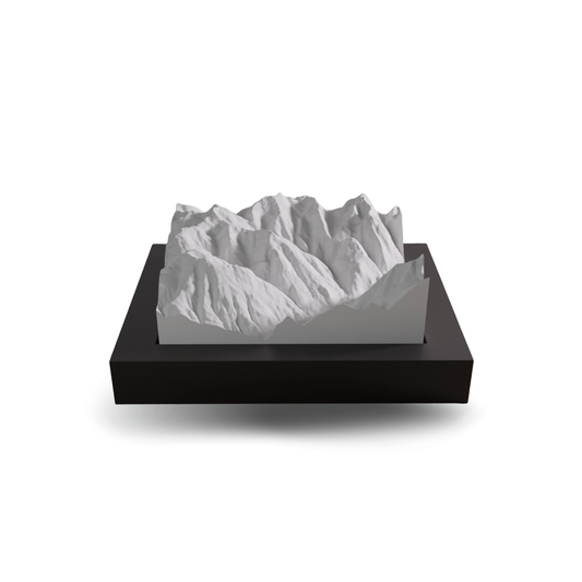 White mountain model on a black base against a white background